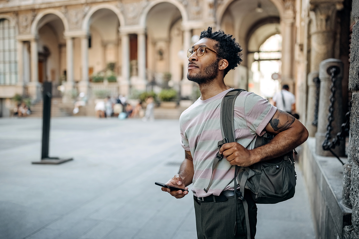 Person using Storydex app on smartphone while exploring historic stone architecture and ancient buildings